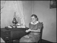 Elderly woman sitting at a small table sewing.gif