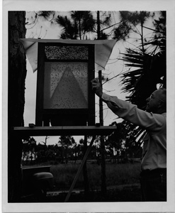 Thumbnail for the first (or only) page of Photograph of scientist inspecting fly trap.